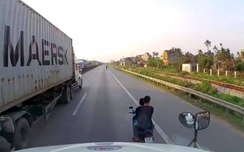 Hai thanh niên đầu trần đi xe máy đánh võng trước đầu xe container