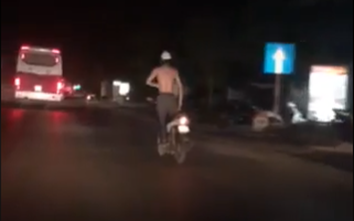 Người đàn ông đứng trên xe máy “biểu diễn” giữa xa lộ